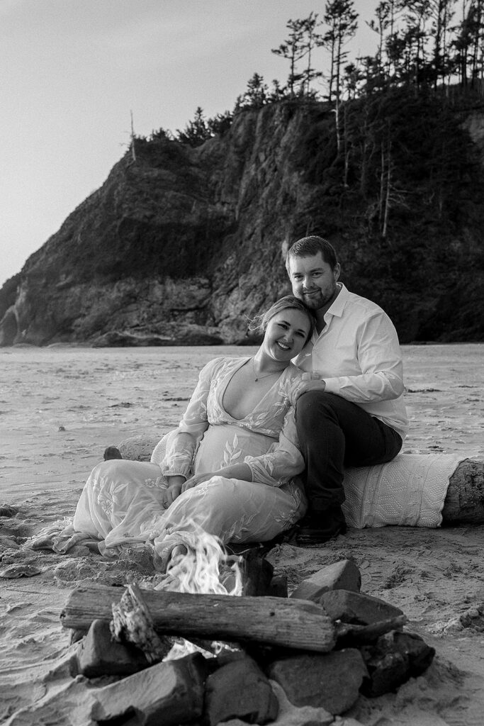 Couple sits by a bonfire on Cannon Beach as part of their elopement experience