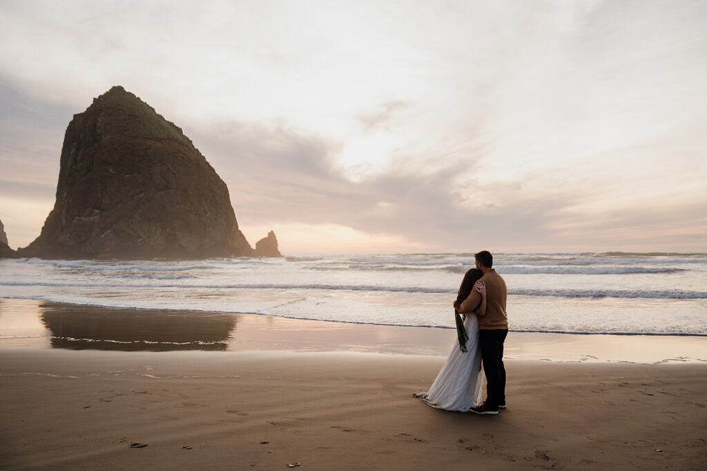 Bride and groom elopement portraits on Cannon Beach with Haystack Rock in the backdrop