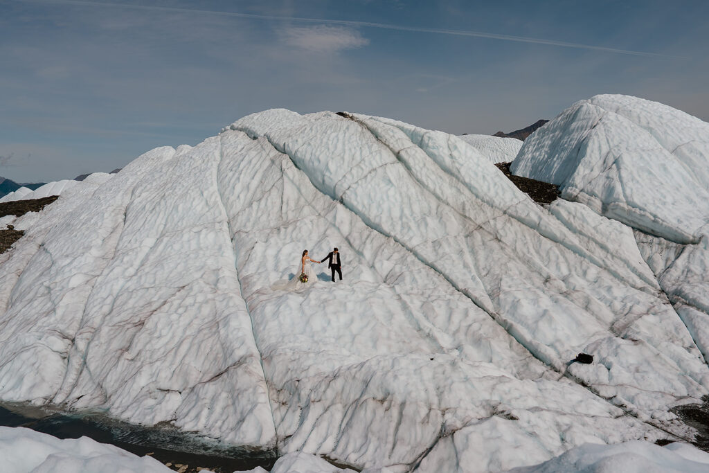 Bride and groom stand on an Alaska Glacier in the summer