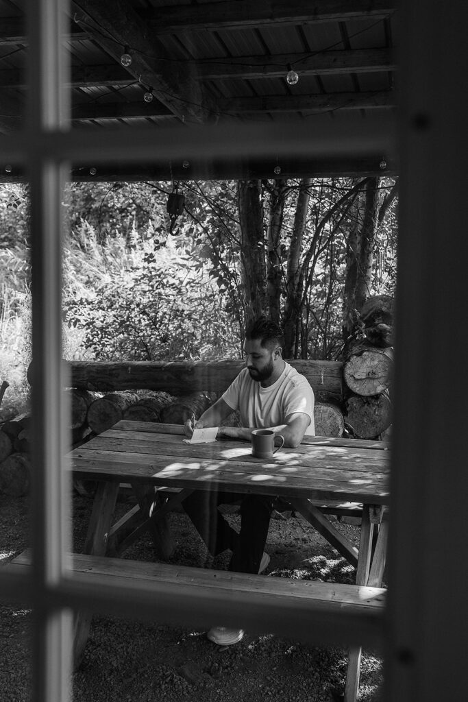 Groom writing vows outside of an Alaska Cabin before ceremony