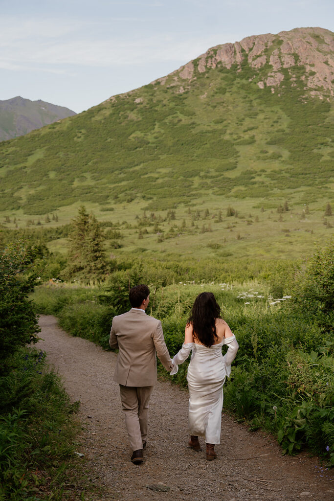 Cinematic golden hour portraits of couple holding hands on a quiet road after eloping in Alaska
