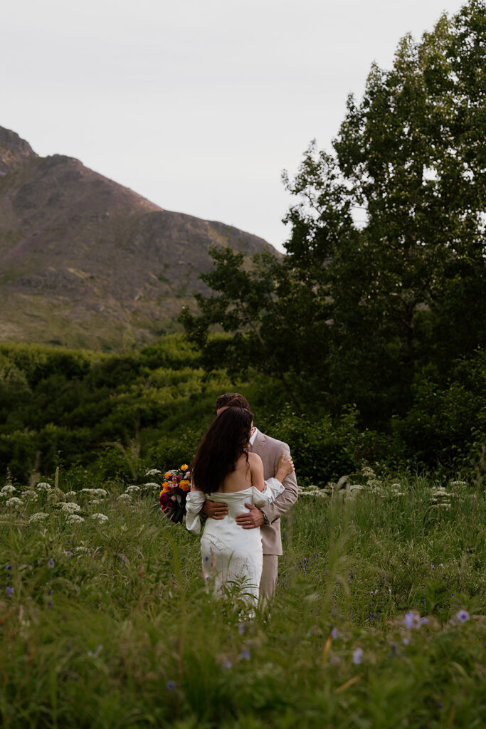 Couple sharing a quiet moment surrounded by wildflowers in the Alaska mountains