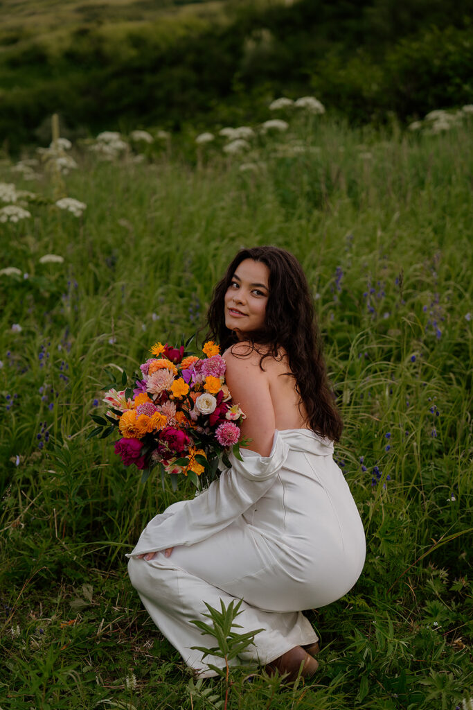 Bride walking through wildflowers with mountains in the background during an Anchorage Alaska elopement