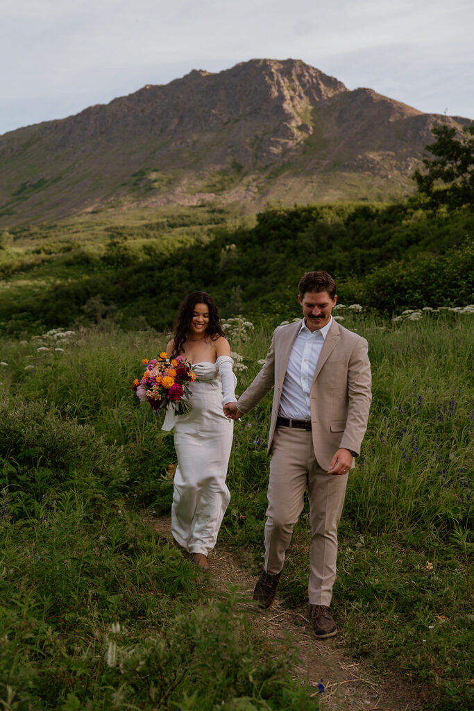 Cinematic golden hour portraits of couple holding hands on a quiet road after eloping in Alaska