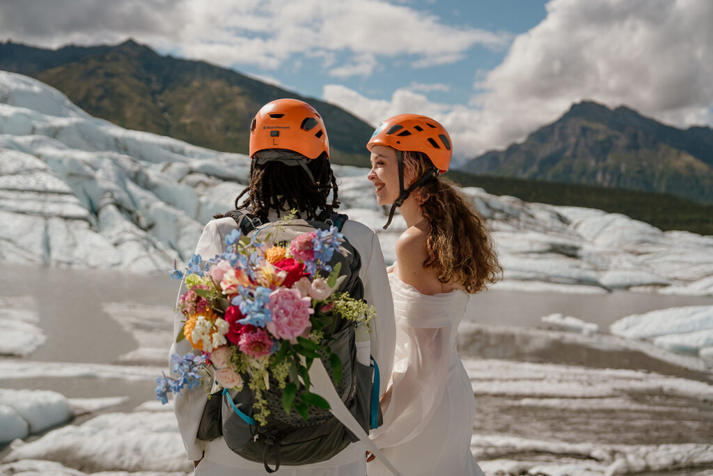 Couple hiking around Matanuska Glacier in Alaska with orange helmets and colorful florals