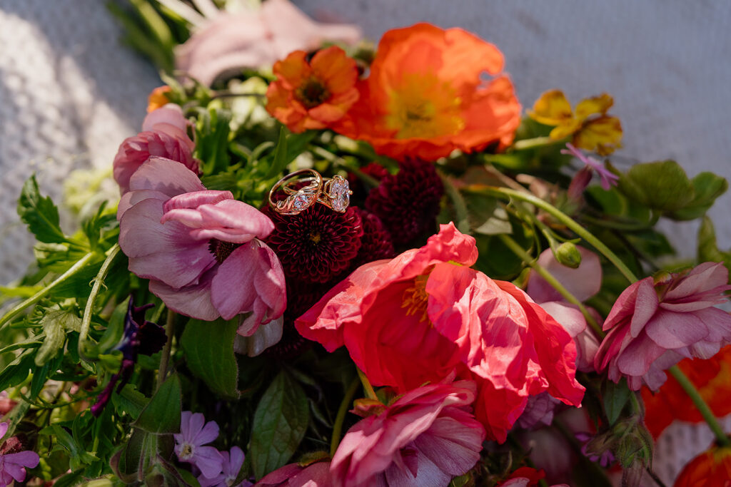Engagement rings sit on a colorful bouquet by Frolic Floral