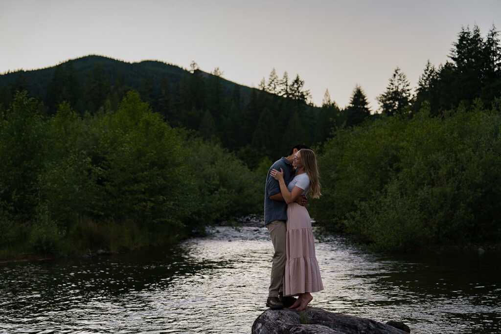 Couple stands on a large rock in Yale Lake at blue hour during their engagement photos
