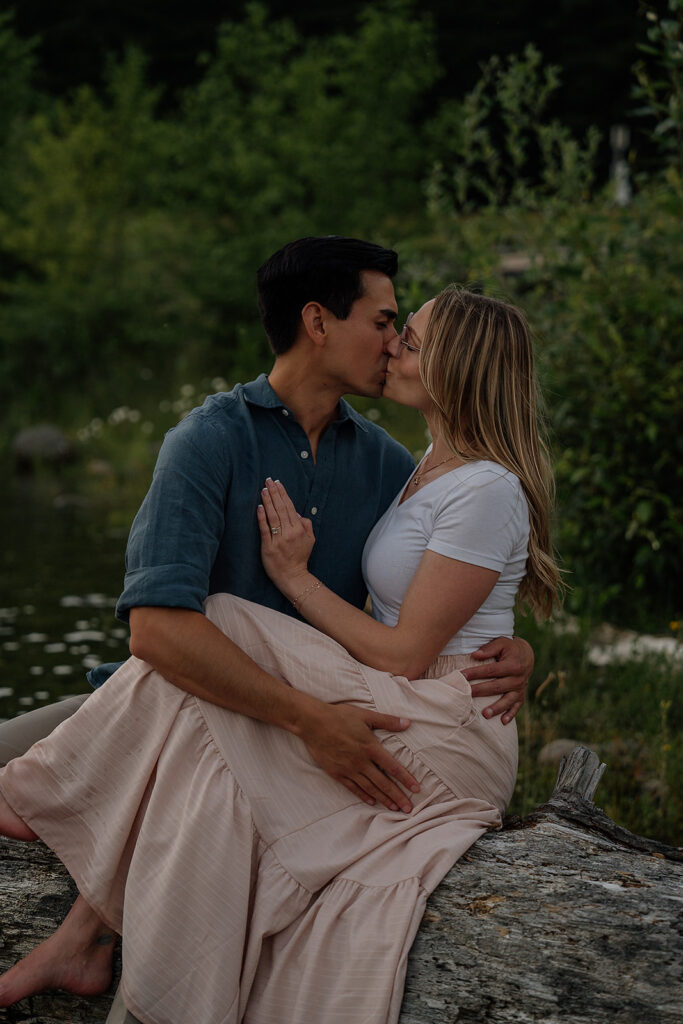 Couple kissing while sitting on a fallen tree