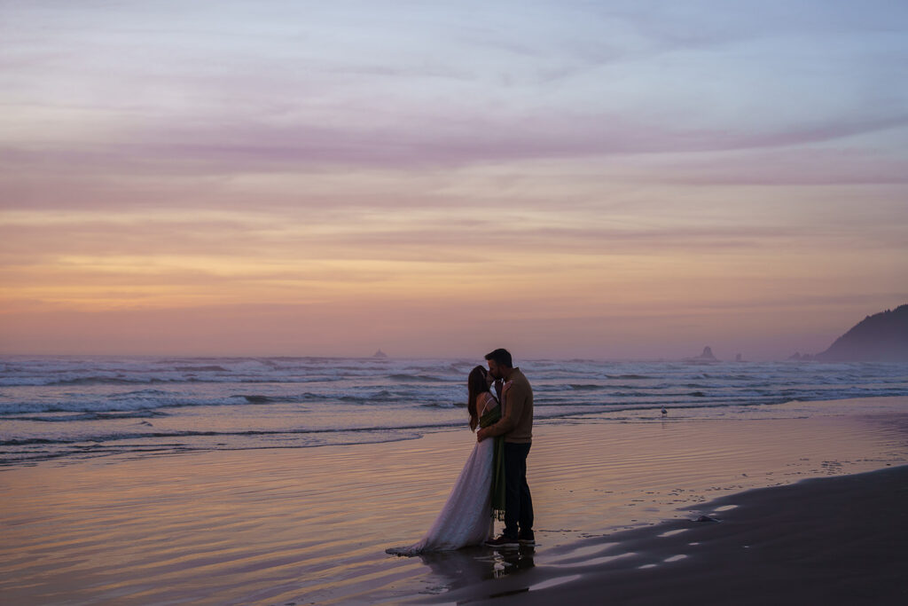 Bride and groom kiss on Cannon Beach at blue hour