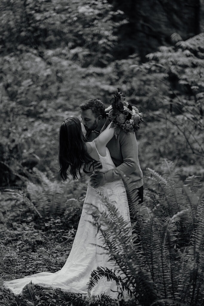 Bride and groom kiss in the forest at Ecola State Park