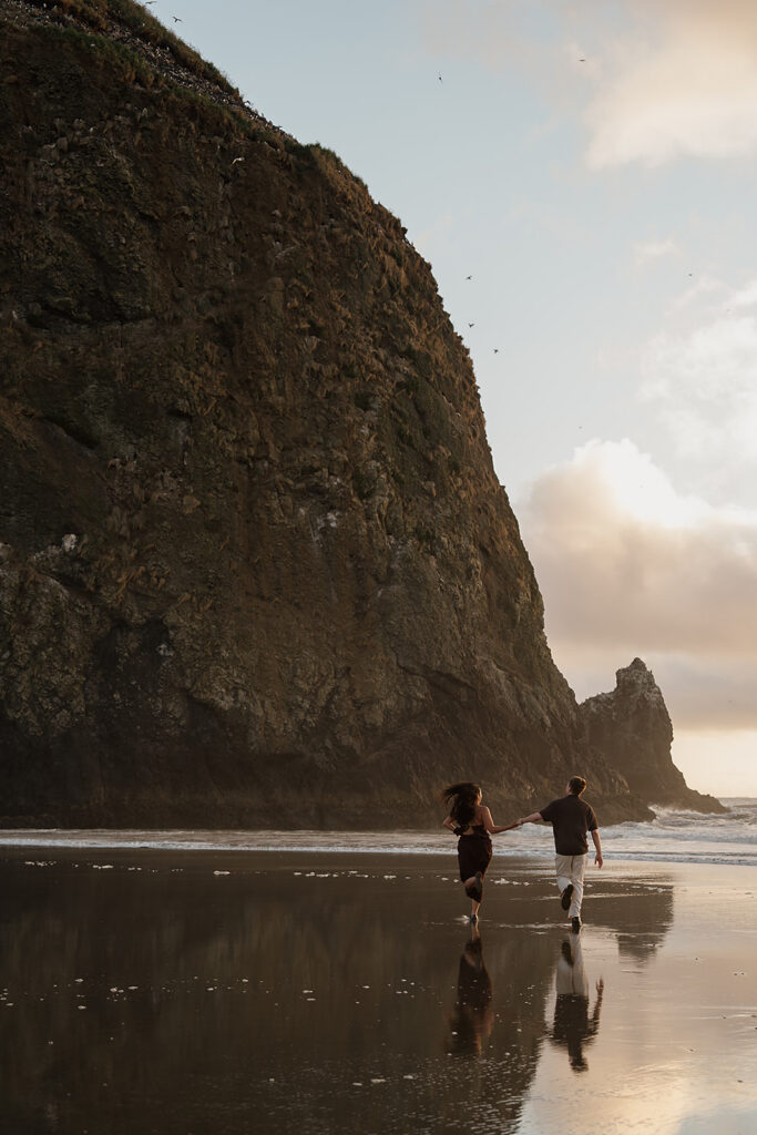 Couple runs on the beach after their surprise marriage proposal on the oregon coast