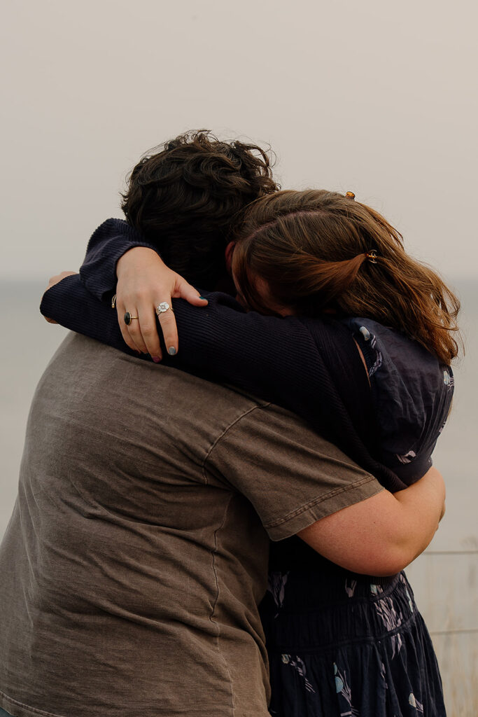 Couple hugs after a surprise proposal at Ecola State Park